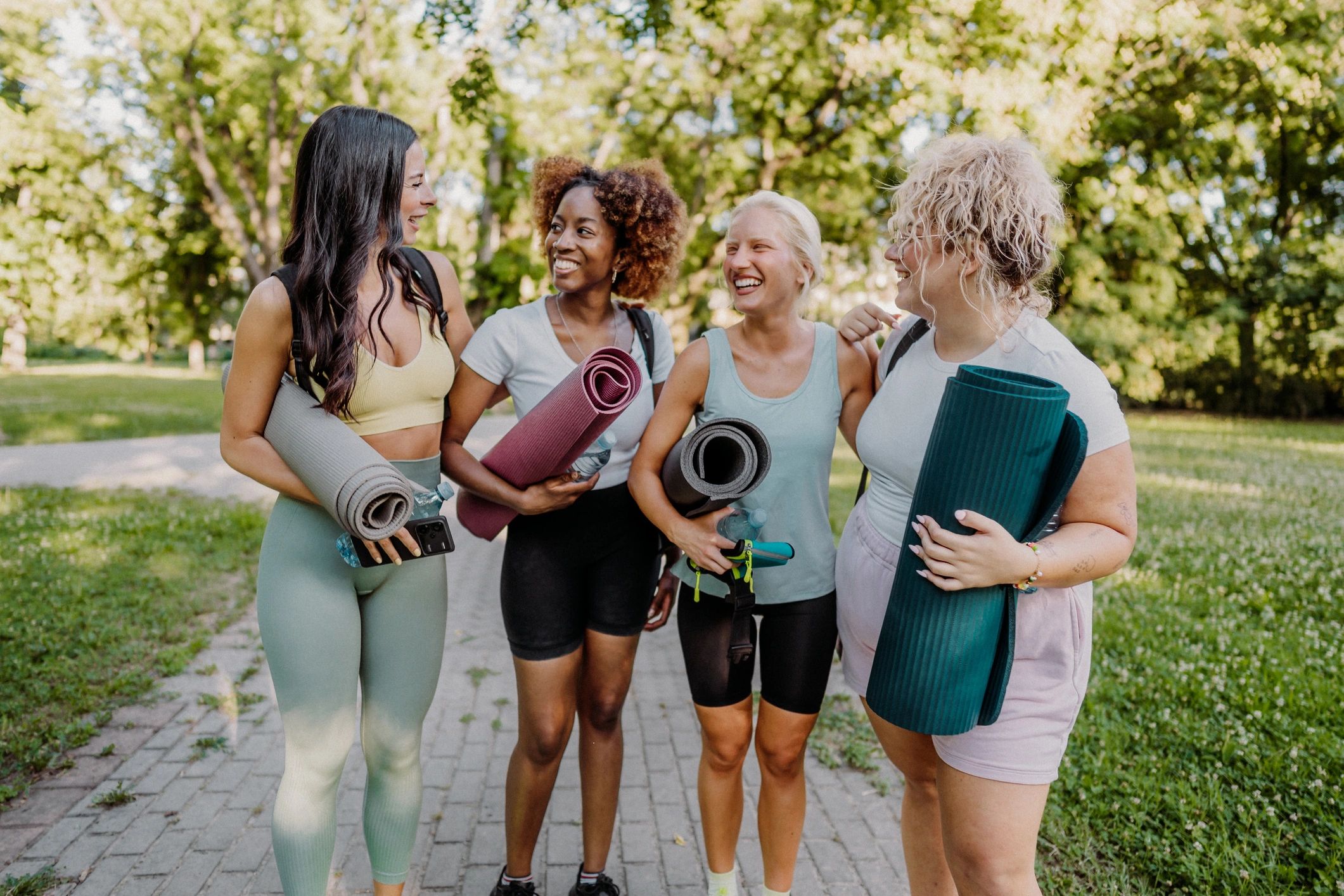 Women with yoga mats at park fitness event